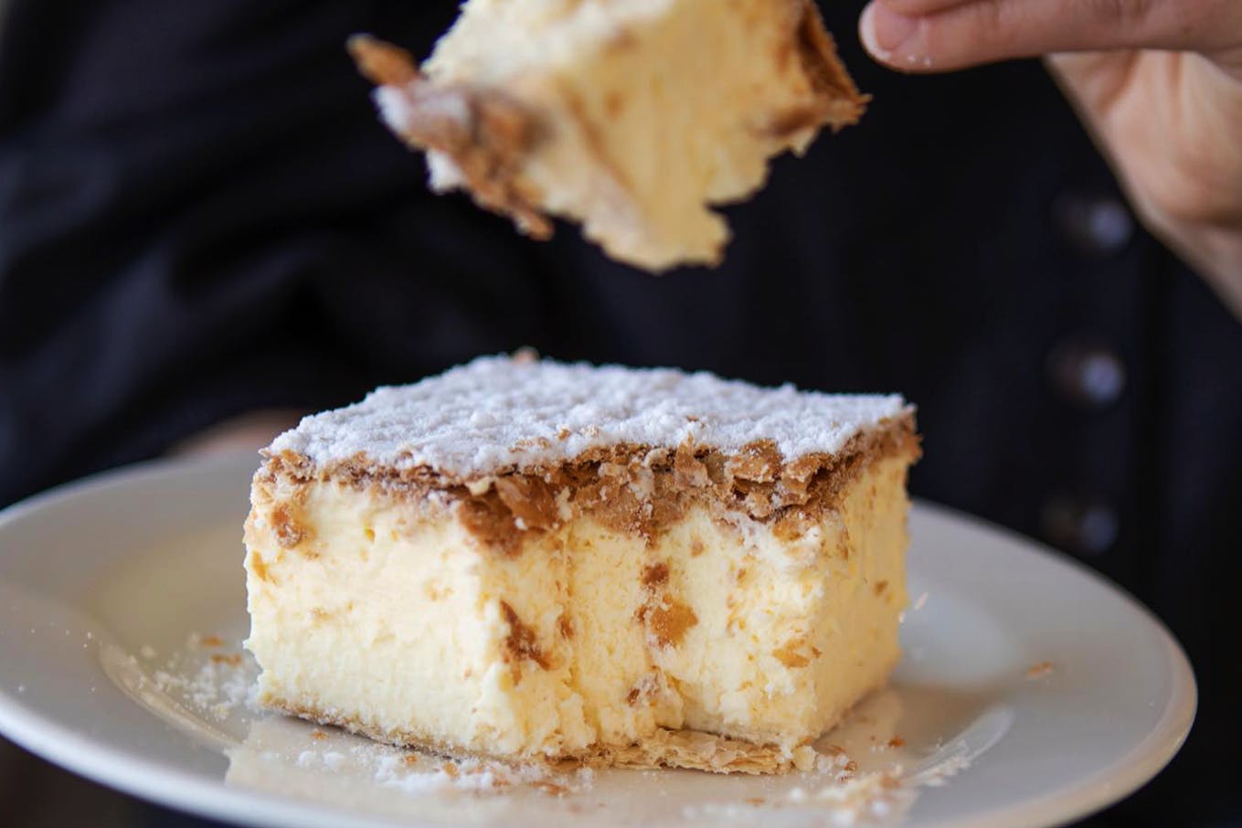 A person taking a forkful of a best vanilla slice melbourne.